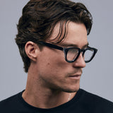 Brutal 4.0 Optical by Tribu Eyewear — Black on Crystal round optical frame, male model side view studio lighting. 