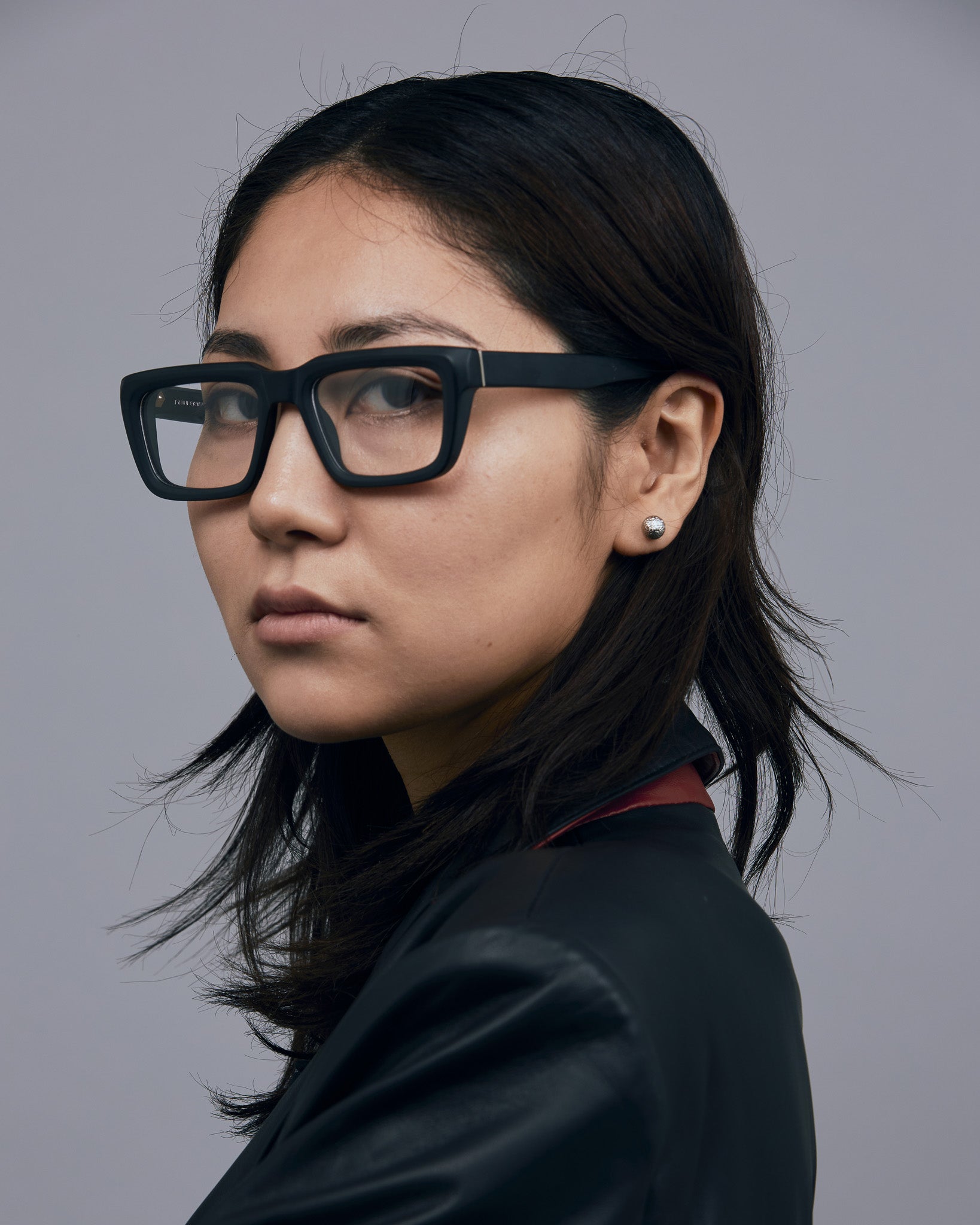 Brutal 5.0 Optical by Tribu Eyewear — Matte Black square optical frame, female model against a grey background. 