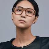 Marley Optical by Tribu Eyewear — Champagne crystal acetate aviator optical frame, female model against a grey background. 