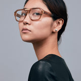 Marley Optical by Tribu Eyewear — Champagne crystal acetate aviator optical frame, female model against a grey background. 