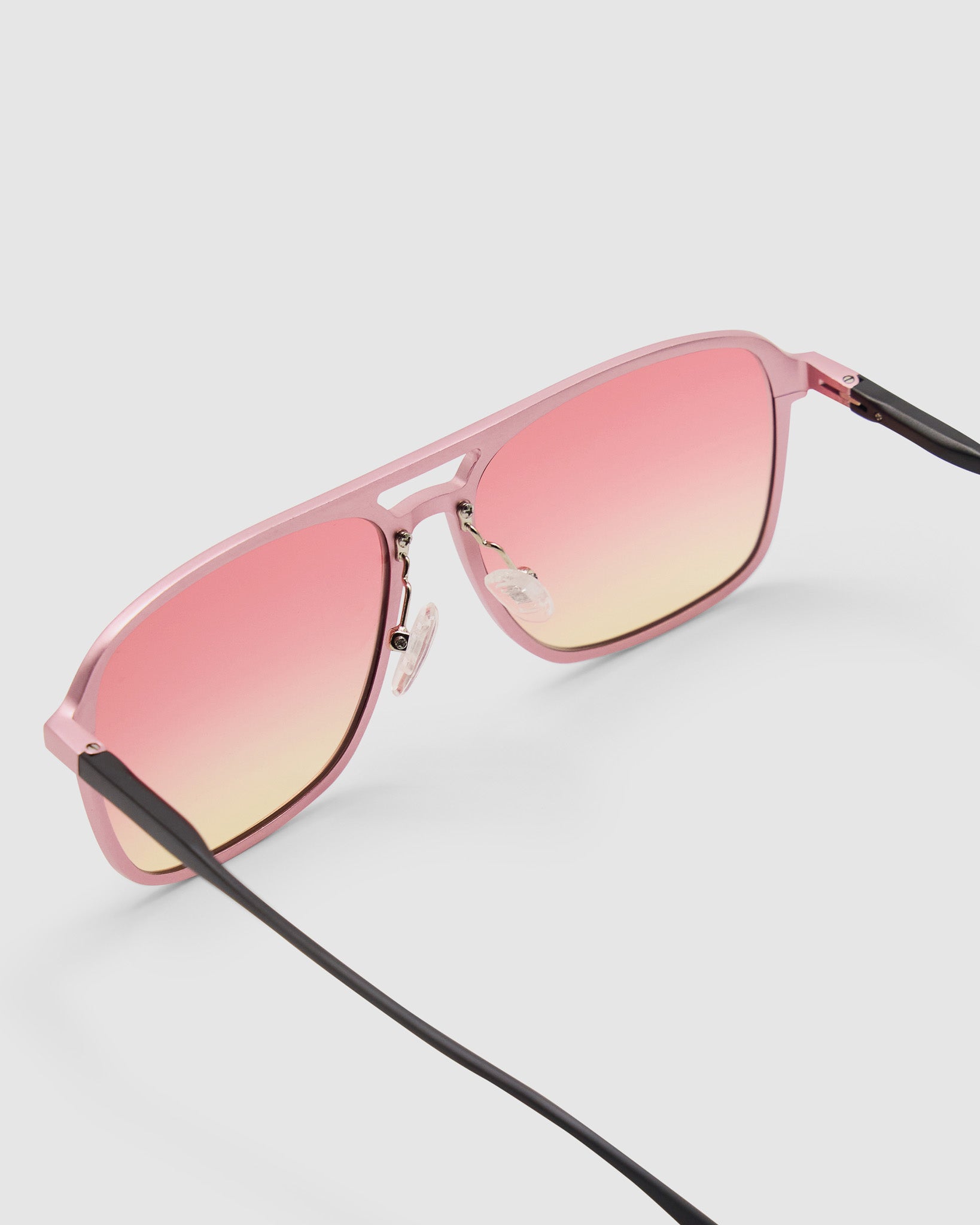 Oscar Sunglasses by Tribu Eyewear — Metallic Pink Aluminium Aviator frame, Sunset lens detailed view against a white background.
