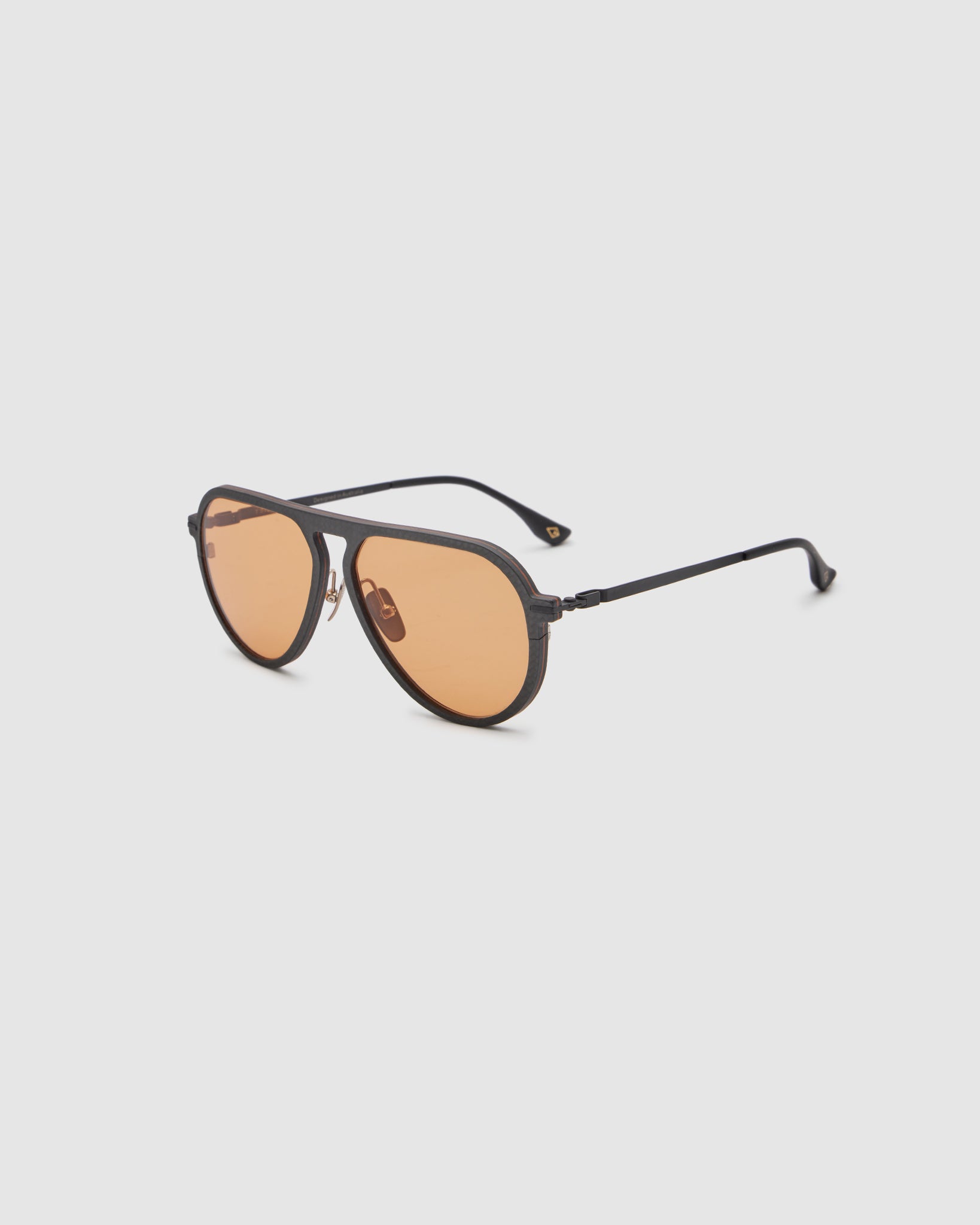 TRIBU Carbon 1.0 Black carbon fibre sunglasses with desert orange lenses, side view.