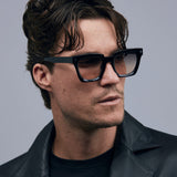 Brutal 1.0 Sunglasses by Tribu Eyewear — Black acetate square frame, dusk lens on male model grey background.