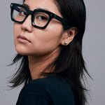 Brutal 1.0 Optical by Tribu Eyewear — Black square optical frame, female model in studio lighting. 
