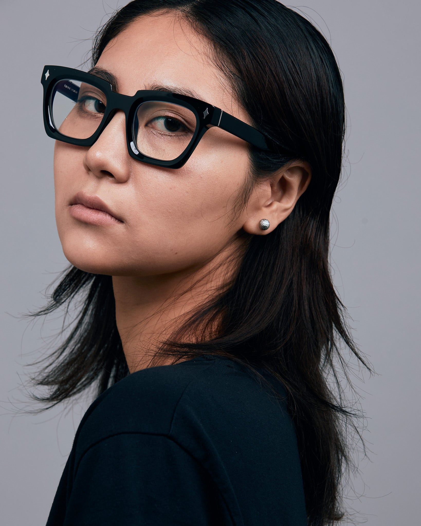 Brutal 1.0 Optical by Tribu Eyewear — Black square optical frame, female model in studio lighting. 
