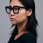 Brutal 1.0 Optical by Tribu Eyewear — Black square optical frame, female model in studio lighting. 
