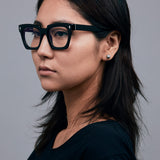 Brutal 1.0 Optical by Tribu Eyewear — Black square optical frame, female model in studio lighting. 
