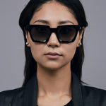 Brutal 1.0 Sunglasses by Tribu Eyewear — Black acetate square frame, grey gradient polarised, female model, grey background.