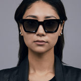 Brutal 1.0 Sunglasses by Tribu Eyewear — Black acetate square frame, grey gradient polarised, female model, grey background.