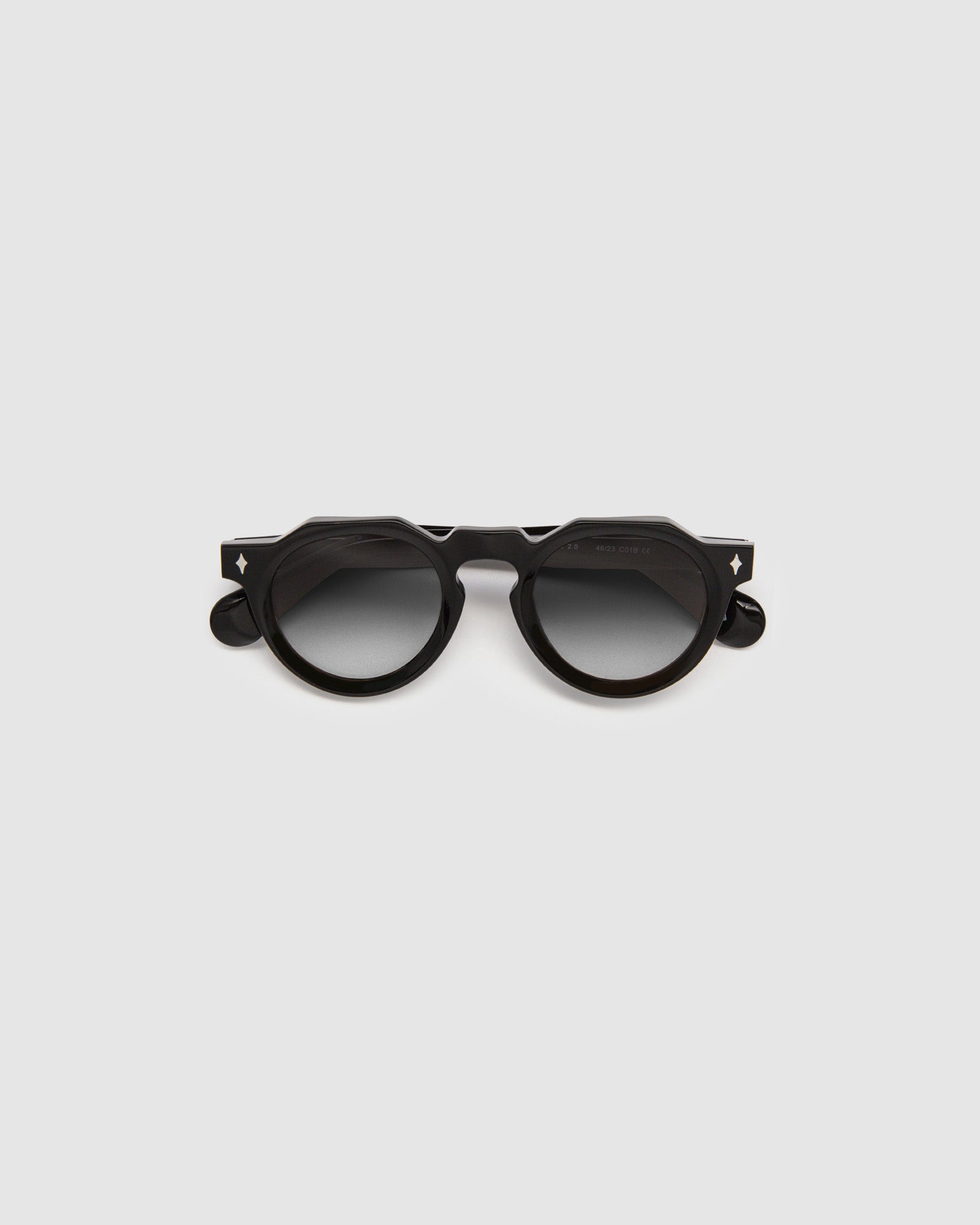 Brutal 2.0 Sunglasses by Tribu Eyewear — Grey grad polarised lens in a black round acetate frame, flat view on grey background.