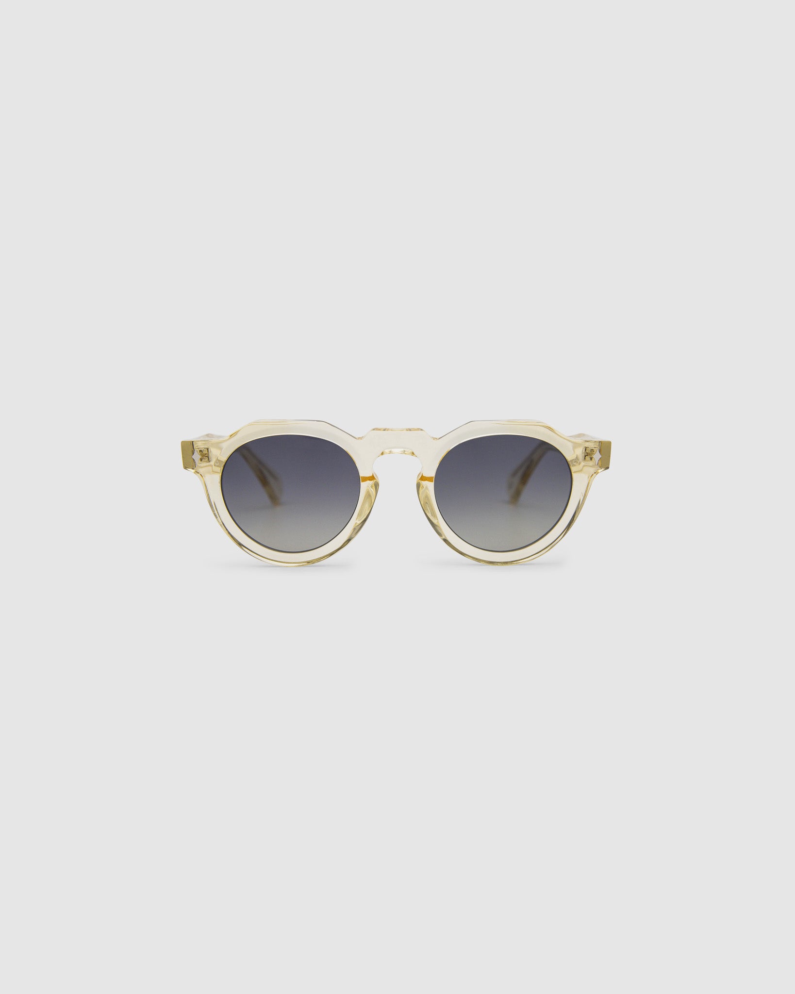 Brutal 2.0 Sunglasses by Tribu Eyewear — Grey grad polarised lens in a Champagne crystal round acetate frame, front view on grey background.