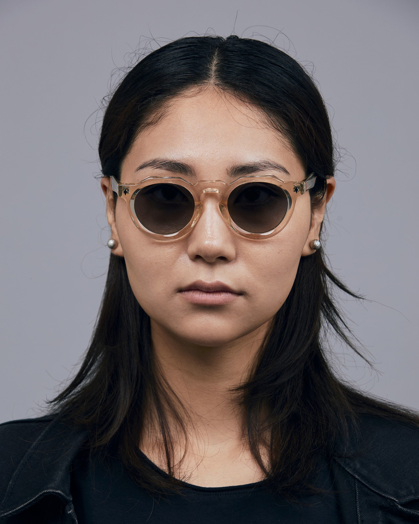 Brutal 2.0 Sunglasses by Tribu Eyewear — Grey grad polarised lens in a Champagne crystal round acetate frame on female model. 
