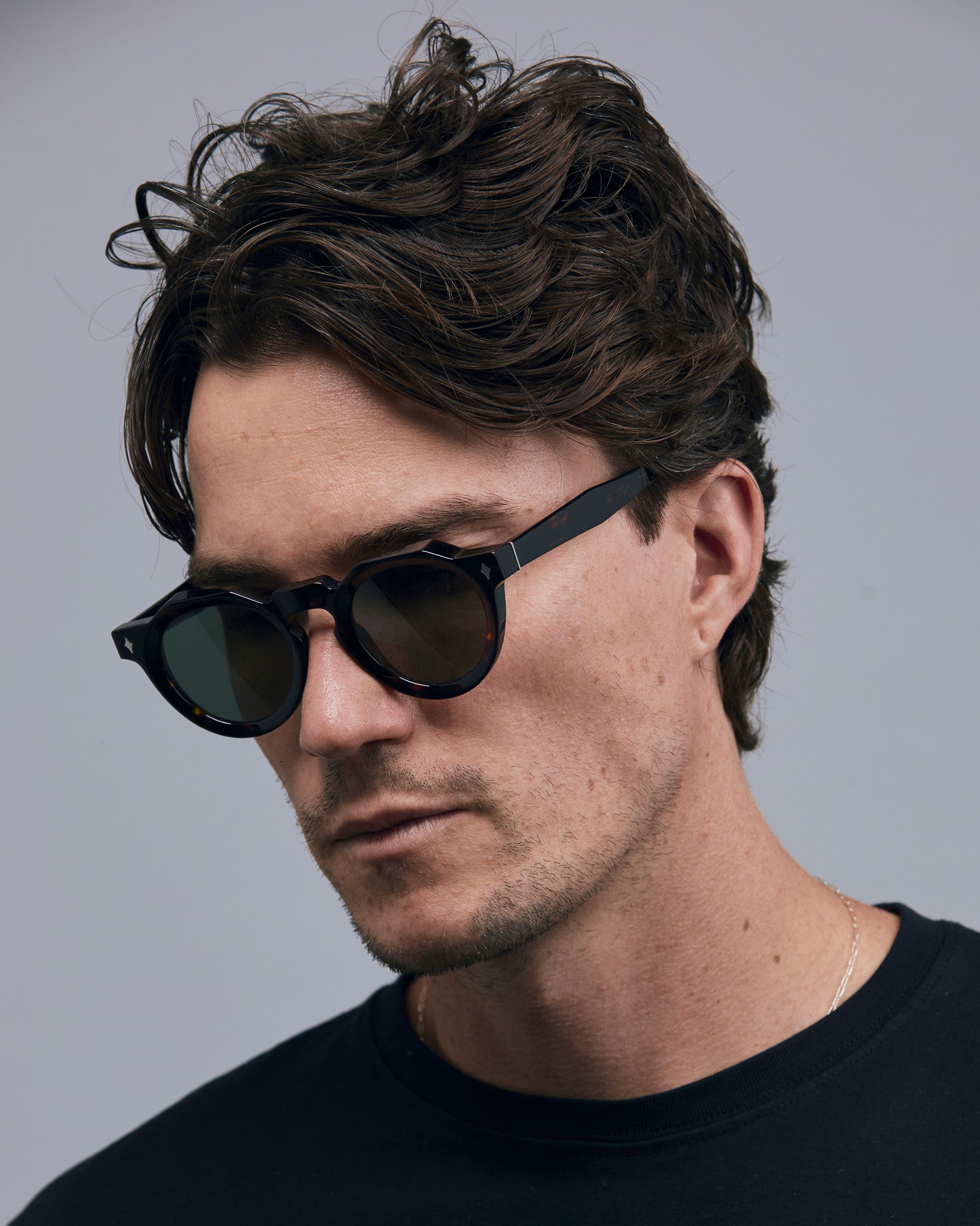 Brutal 2.0 Sunglasses by Tribu Eyewear — Green polarised lens in a round tort acetate frame on a male model grey background.