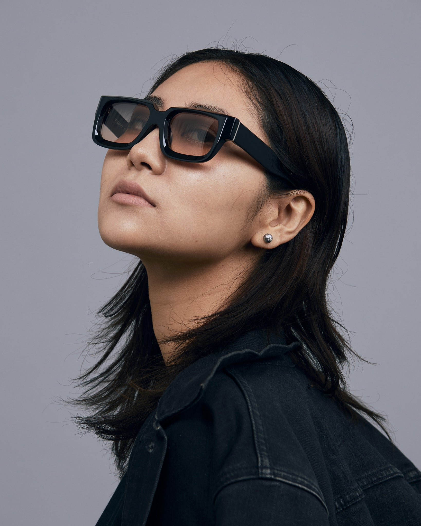 Brutal 3.0  Sunglasses by Tribu Eyewear — Black square acetate frame, dusk lens, on female model light grey background.