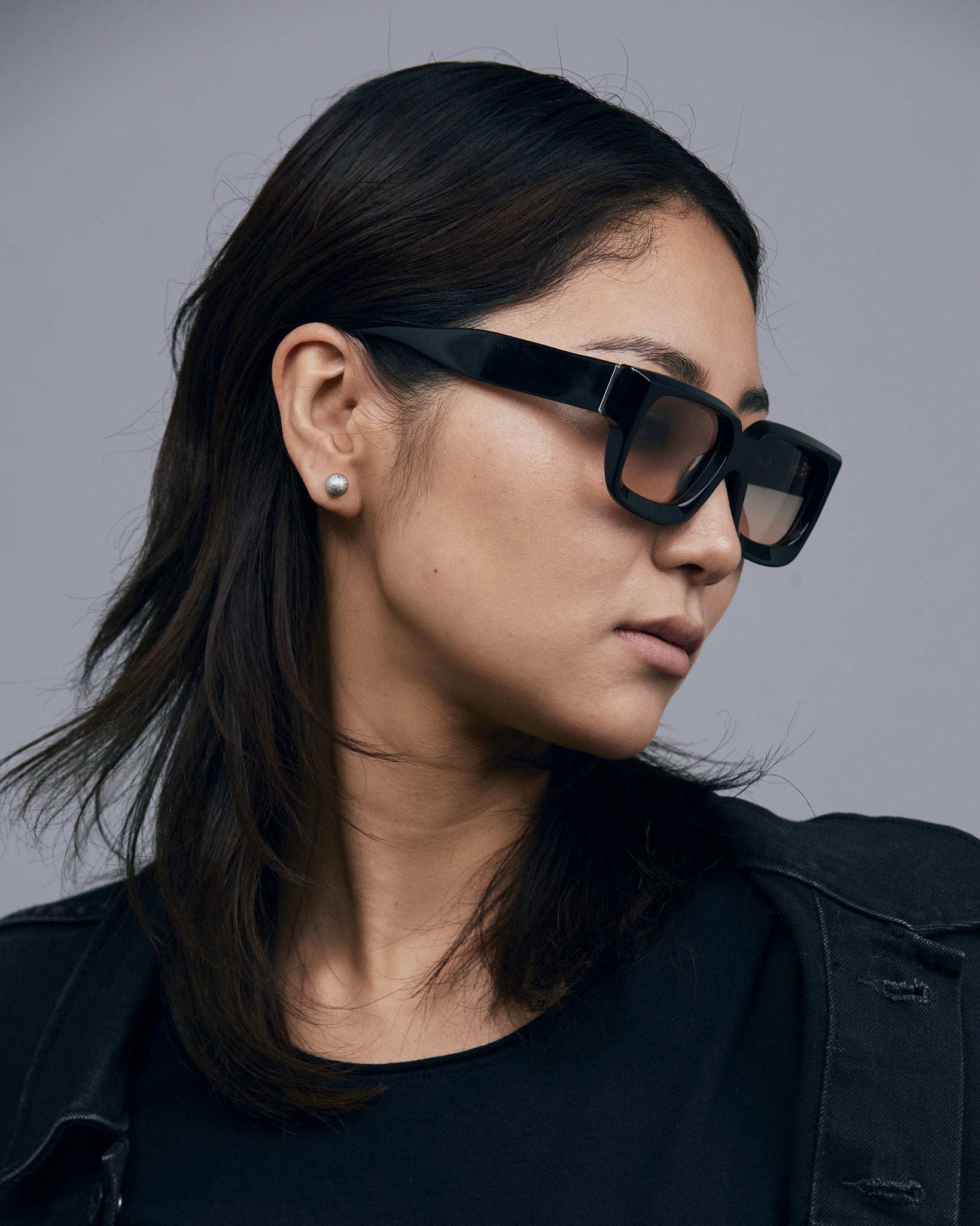 Brutal 3.0  Sunglasses by Tribu Eyewear — Black square acetate frame, dusk lens, on female model light grey background.