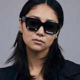 Brutal 3.0 Polarised Sunglasses by Tribu Eyewear — Black square frame, front view female model light grey background.