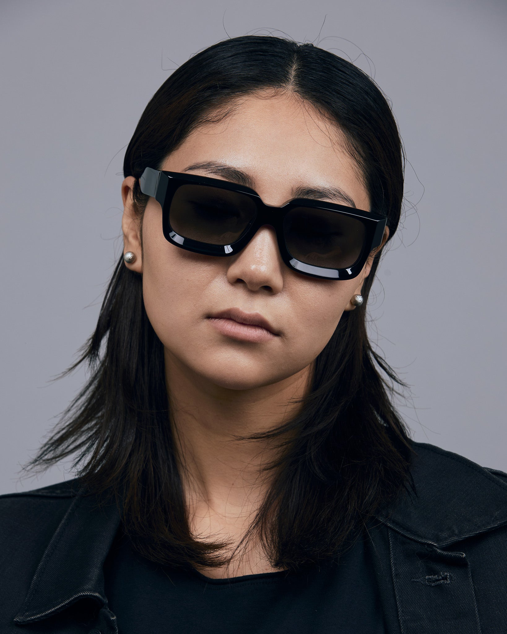 Brutal 3.0 Polarised Sunglasses by Tribu Eyewear — Black square frame, front view female model light grey background.