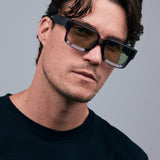 Brutal 3.0  Sunglasses by Tribu Eyewear — Black square acetate frame, sage lens, male model light grey background.