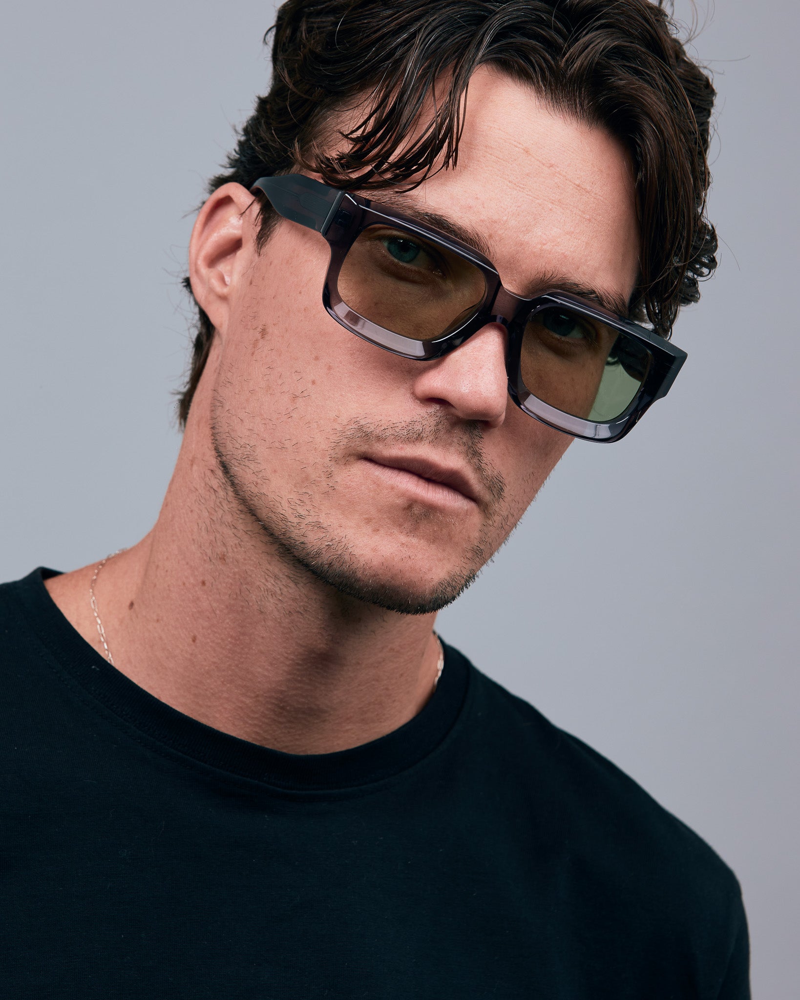 Brutal 3.0  Sunglasses by Tribu Eyewear — Black square acetate frame, sage lens, male model light grey background.