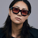 Brutal 3.0  Sunglasses by Tribu Eyewear — Black square acetate frame, sunset lens, female model light grey background.