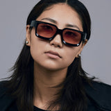 Brutal 3.0  Sunglasses by Tribu Eyewear — Black square acetate frame, sunset lens, female model light grey background.