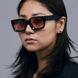 Brutal 3.0  Sunglasses by Tribu Eyewear — Black square acetate frame, sunset lens, female model light grey background.