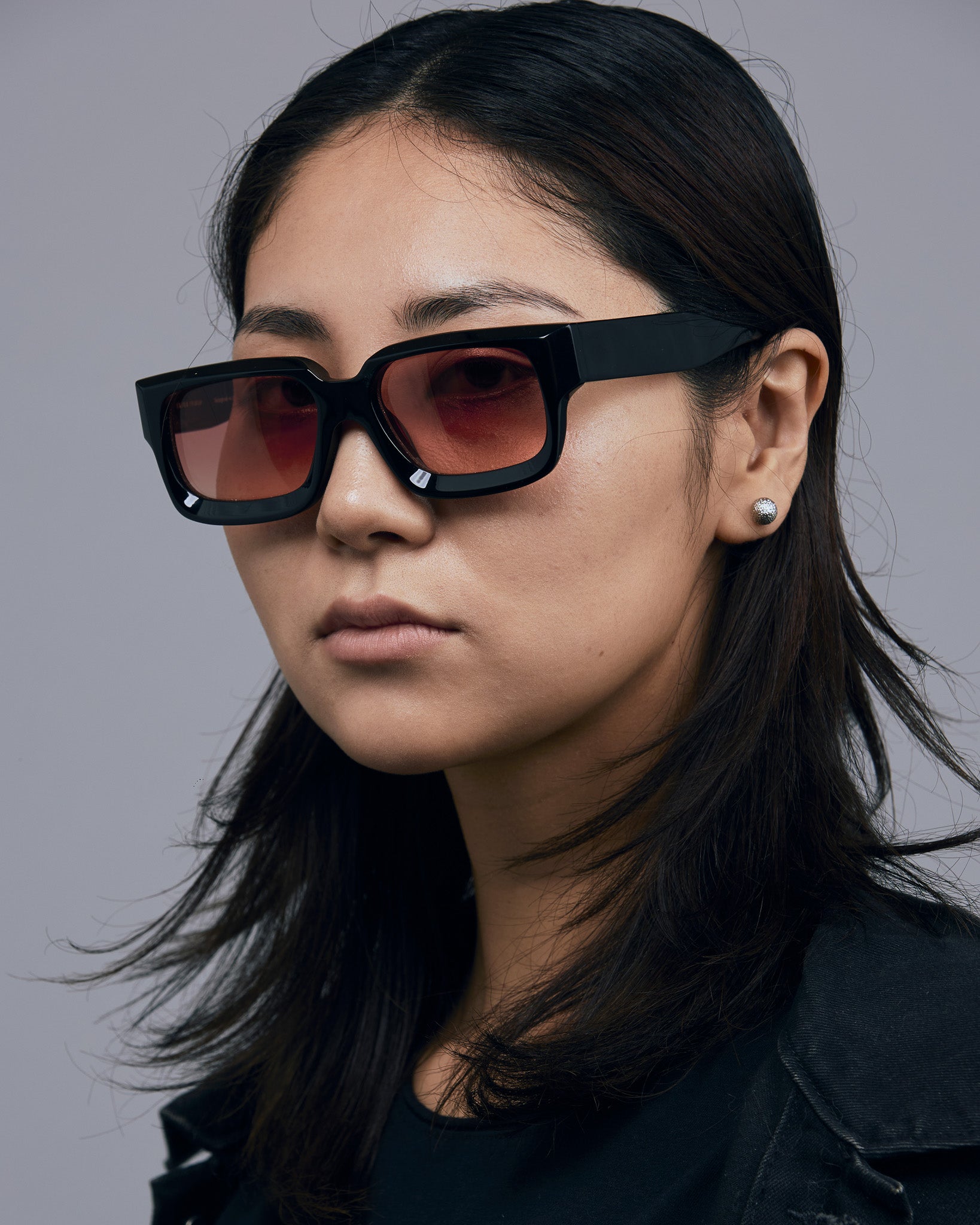 Brutal 3.0  Sunglasses by Tribu Eyewear — Black square acetate frame, sunset lens, female model light grey background.