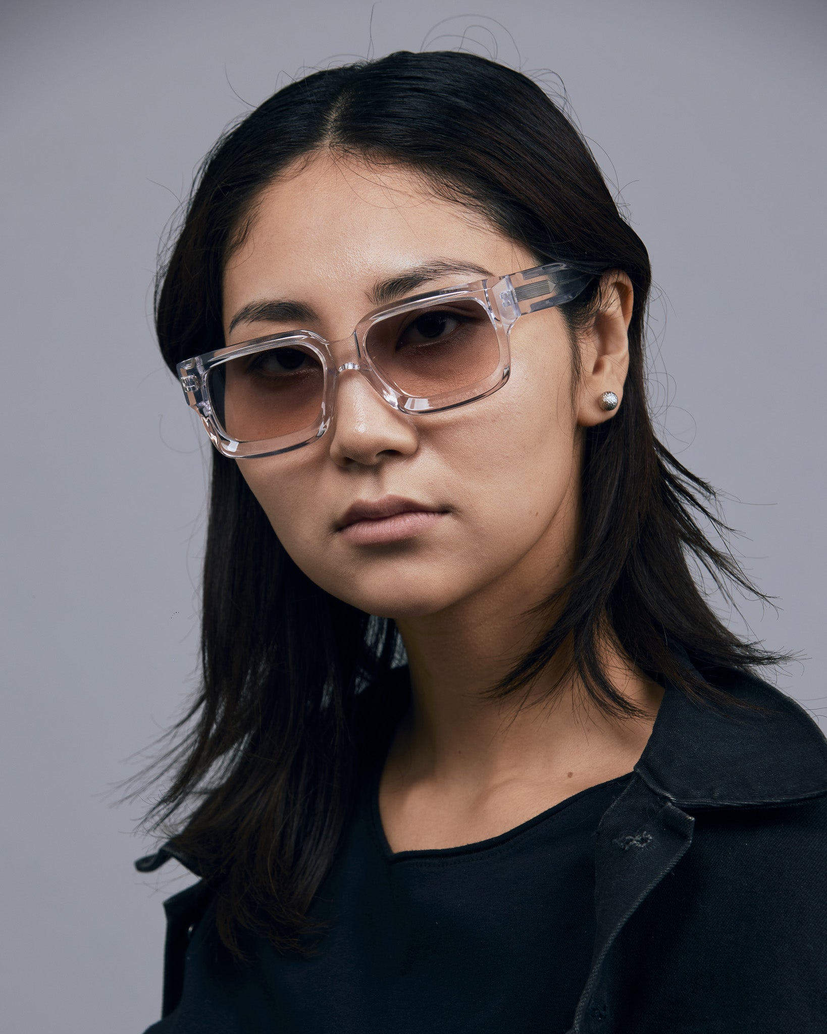 Brutal 3.0  Sunglasses by Tribu Eyewear — Crystal square acetate frame, dusk lens, female model light grey background.