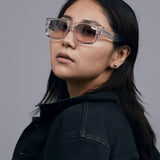 Brutal 3.0  Sunglasses by Tribu Eyewear — Crystal square acetate frame, dusk lens, female model light grey background.