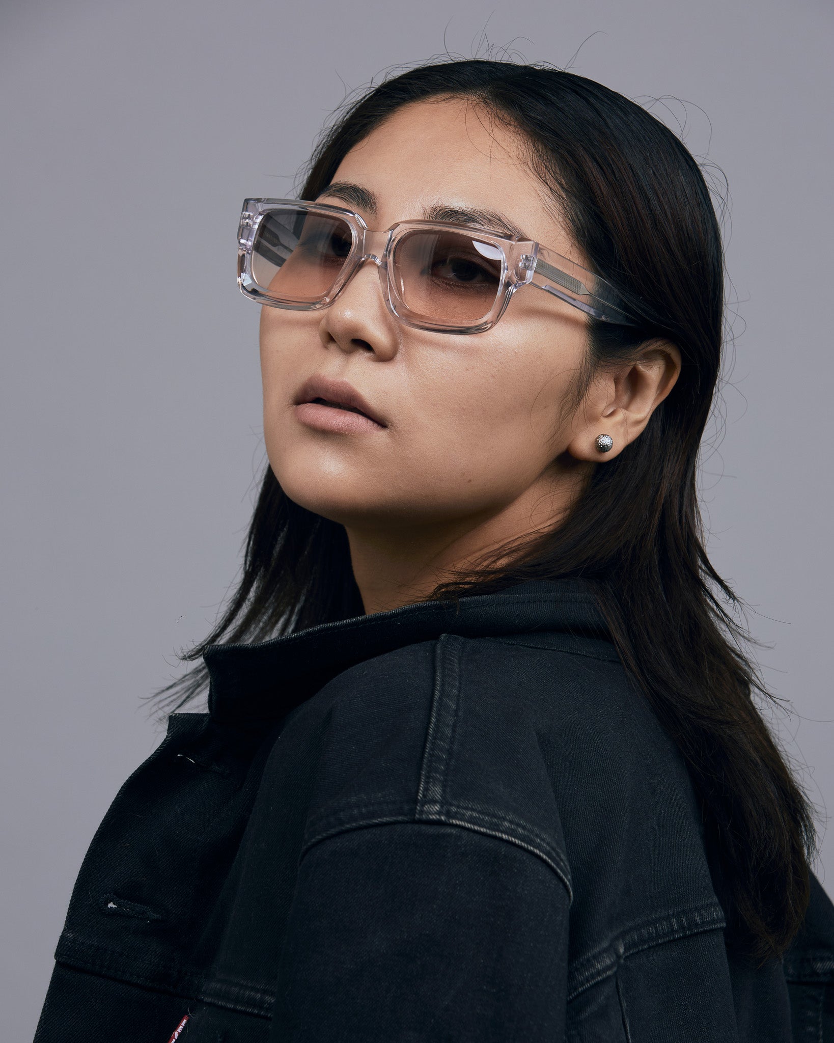 Brutal 3.0  Sunglasses by Tribu Eyewear — Crystal square acetate frame, dusk lens, female model light grey background.