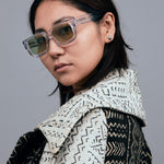 Brutal 3.0  Sunglasses by Tribu Eyewear — Crystal square acetate frame, sage lens, female model light grey background.