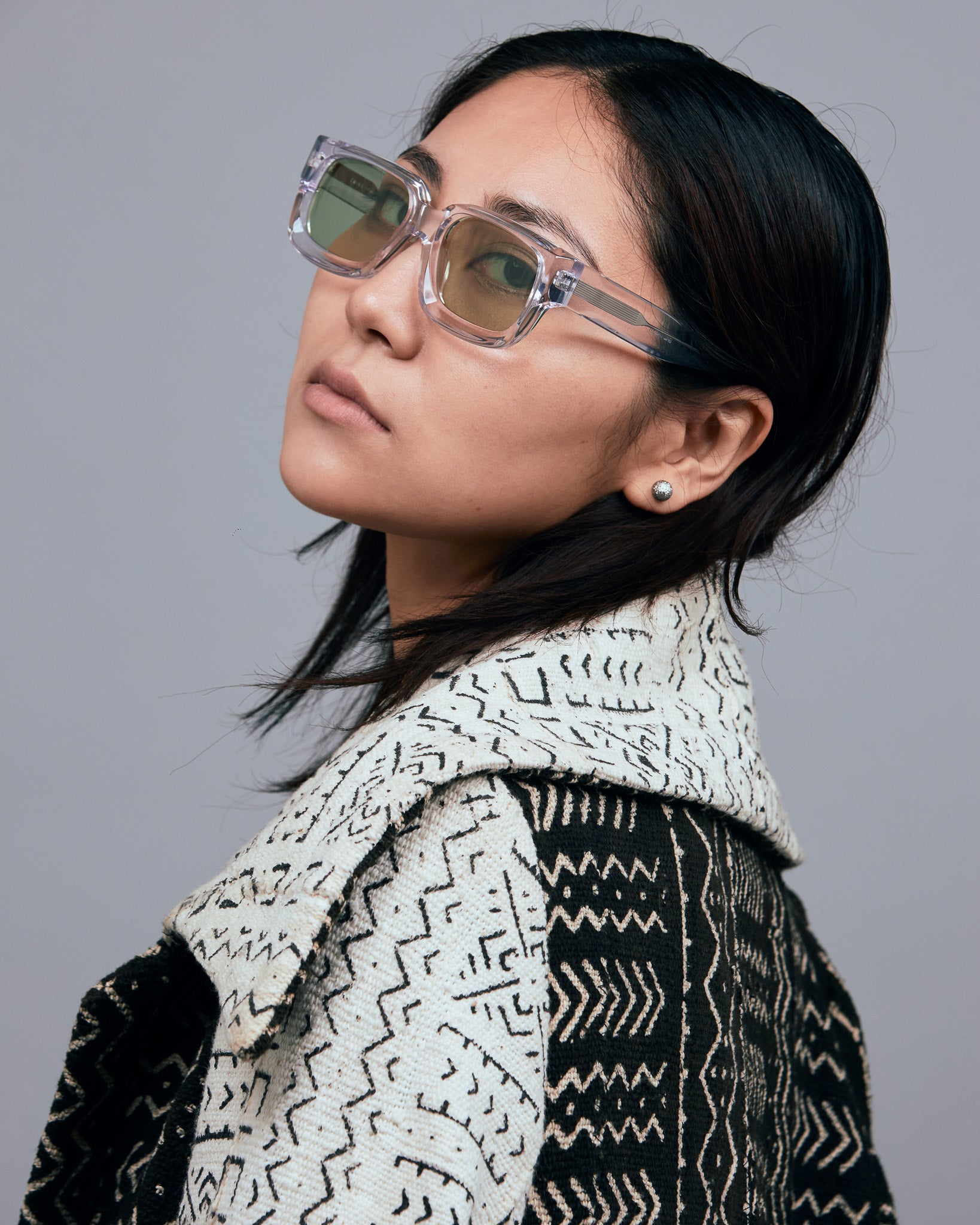 Brutal 3.0  Sunglasses by Tribu Eyewear — Crystal square acetate frame, sage lens, female model light grey background.