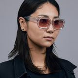 Brutal 3.0  Sunglasses by Tribu Eyewear — Crystal square acetate frame, sunset lens, on female model light grey background.