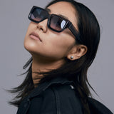 Brutal 3.0 Crystal Sunglasses by Tribu Eyewear — Smoke Crystal square acetate frame, Deep Ocean lens, female model light grey background.