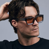Brutal 3.0  Sunglasses by Tribu Eyewear — Smoke Crystal square acetate frame, desert orange lens, male model light grey background.