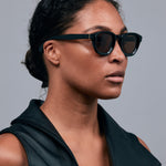 Brutal 4.0 Polarised Sunglasses by Tribu Eyewear — Black Round acetate frame, brown lens, on female light grey background.