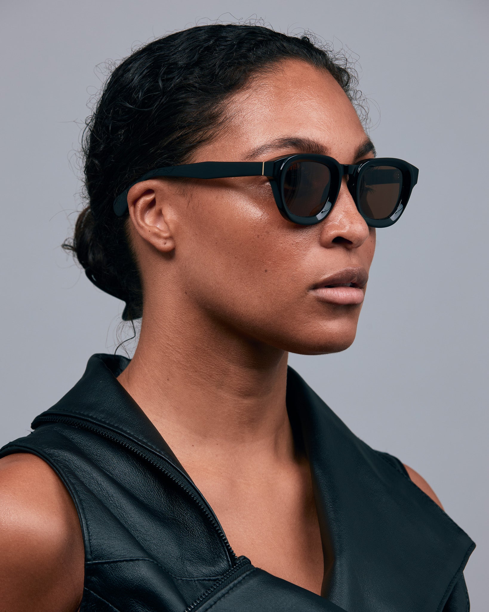 Brutal 4.0 Polarised Sunglasses by Tribu Eyewear — Black Round acetate frame, brown lens, on female light grey background.
