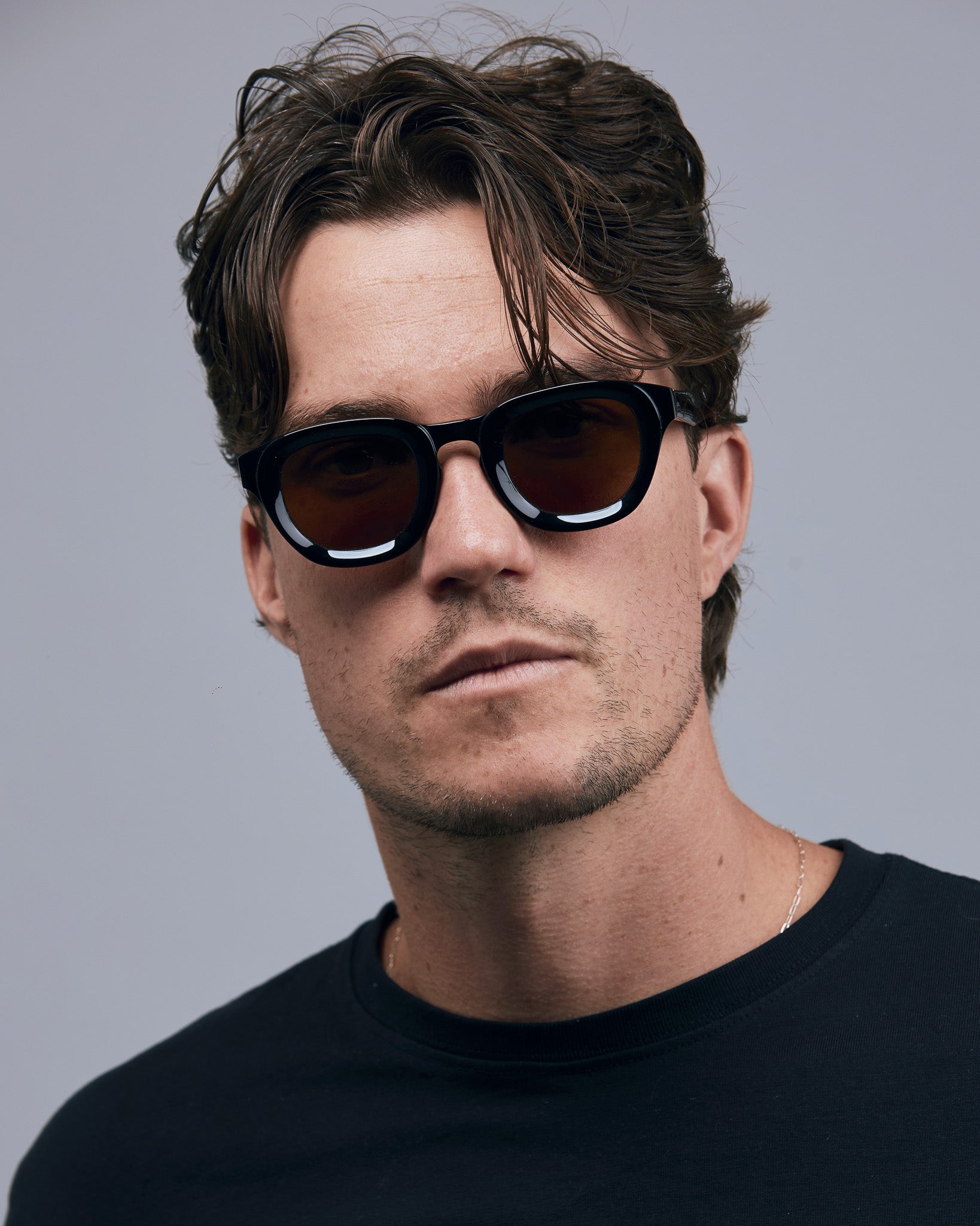 Brutal 4.0 Polarised Sunglasses by Tribu Eyewear — Black Round acetate frame, brown lens, on male light grey background.