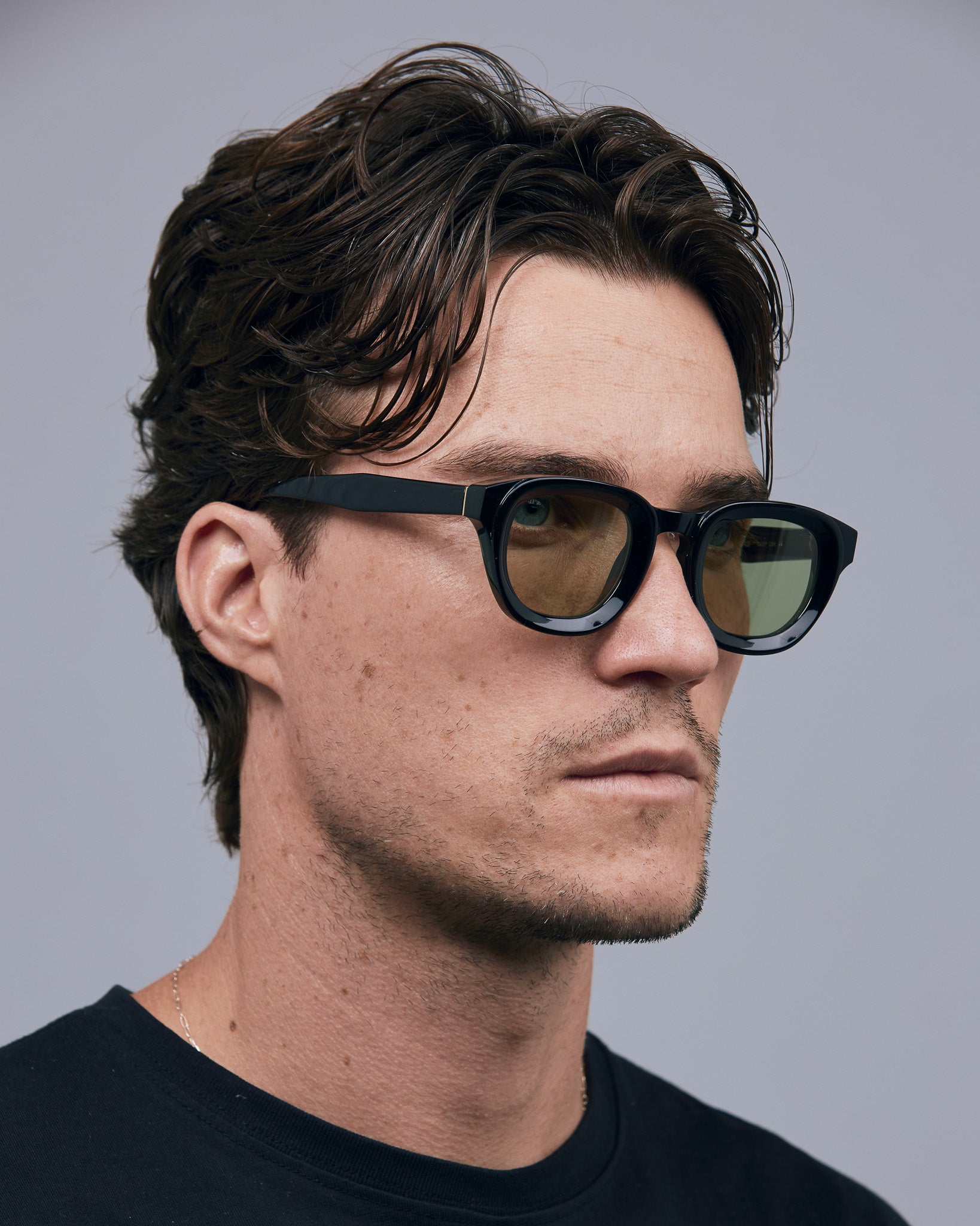 Brutal 4.0 Sunglasses by Tribu Eyewear — Black round acetate frame, sage lens, on male light grey background.