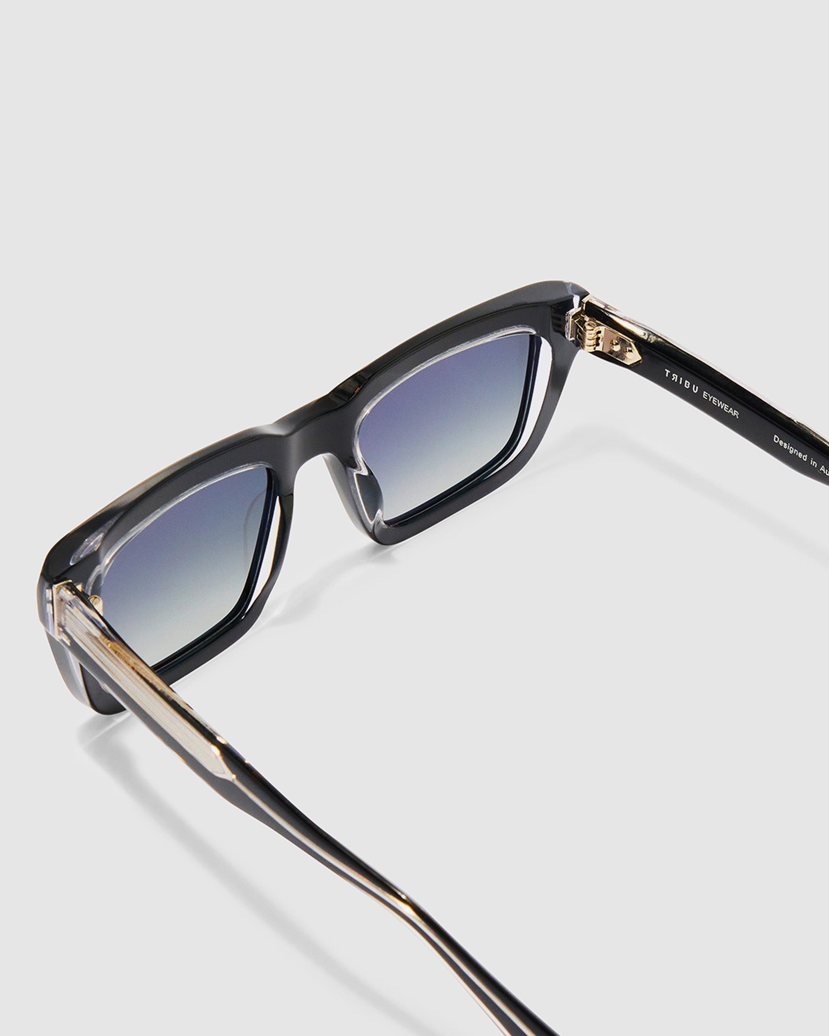 Brutal 5.0 Polarised Sunglasses by Tribu Eyewear — Black on Crystal rectangular acetate frame, grey lens, detailed view light grey background.
