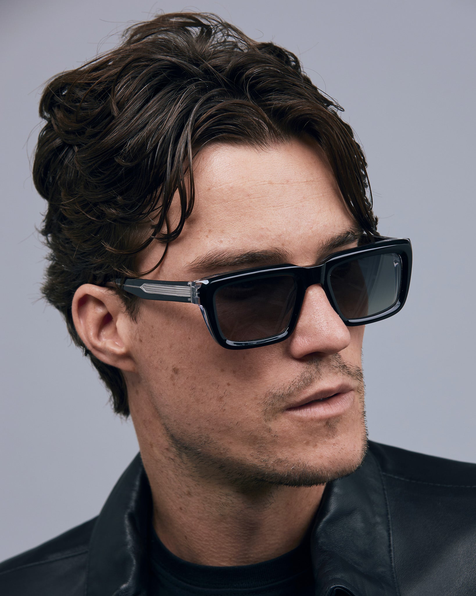 Brutal 5.0 Polarised Sunglasses by Tribu Eyewear — Black on Crystal rectangular acetate frame, grey lens, on male light grey background.