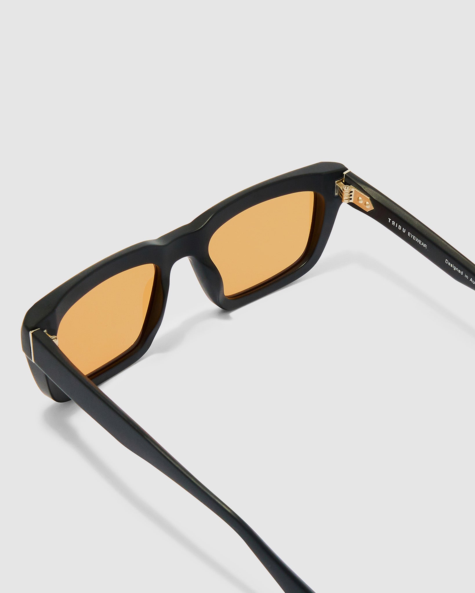 Brutal 5.0 Sunglasses by Tribu Eyewear — Matte black rectangular acetate frame, desert orange lens, detailed view  light grey background.