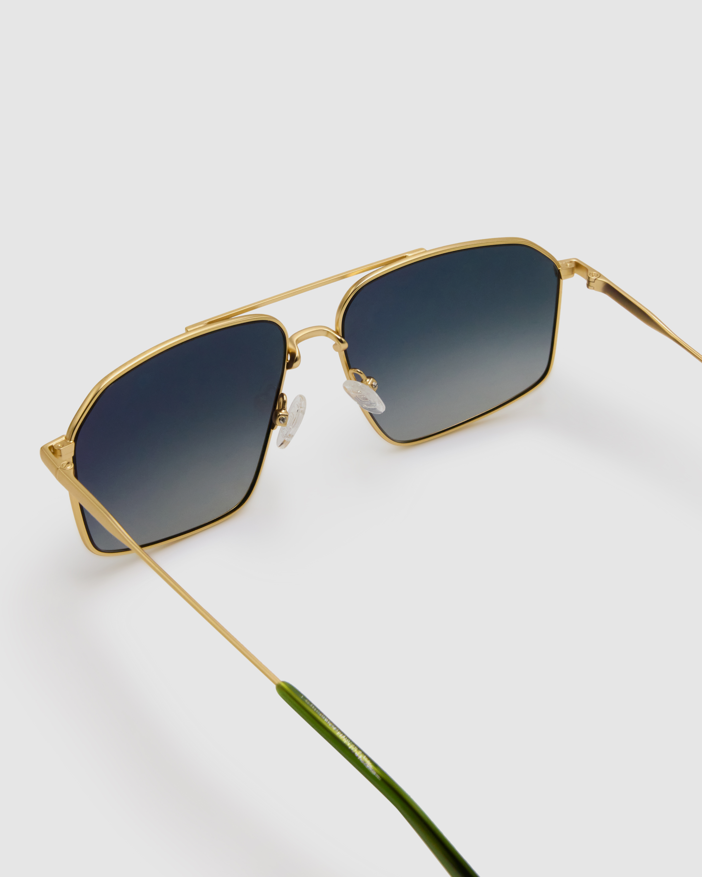 Fonda Sunglasses by Tribu Eyewear — Grey grad polarised lens in a brushed gold metal aviator frame, detailed view on a grey background.