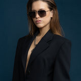Fonda Sunglasses by Tribu Eyewear — Grey grad polarised lens in a brushed gold metal aviator frame on a female model. 