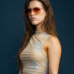 Fonda Gold Sunglasses by Tribu Eyewear  — Fine wire metal aviator frame, sunset tint lens on female model. 