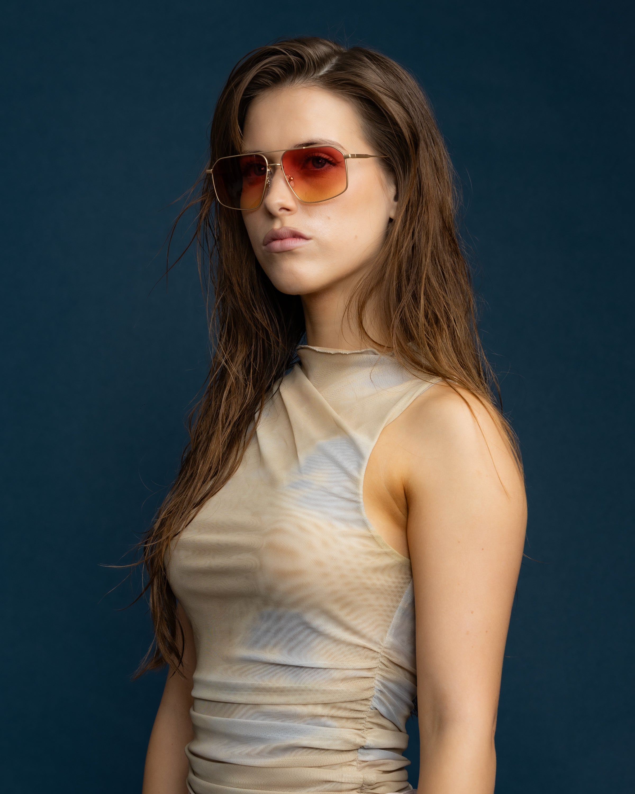 Fonda Gold Sunglasses by Tribu Eyewear  — Fine wire metal aviator frame, sunset tint lens on female model. 