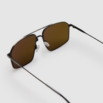 Fonda Sunglasses by Tribu Eyewear — Brown polarised lens in a gun metal aviator frame, detailed view on a grey background.