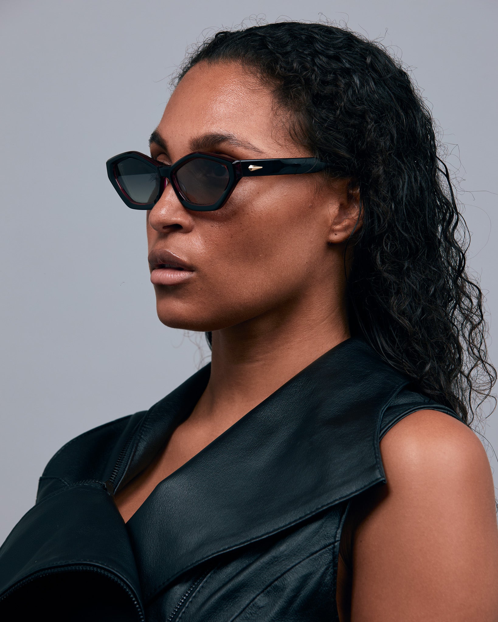 Franky Polarised Sunglasses by Tribu Eyewear — Black on Red Acetate Cat-eye frame with grey lens, side female model grey background.