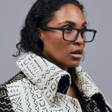 Gentleman Optical by Tribu Eyewear — matte black rectangular optical frame, female model on a grey background. 