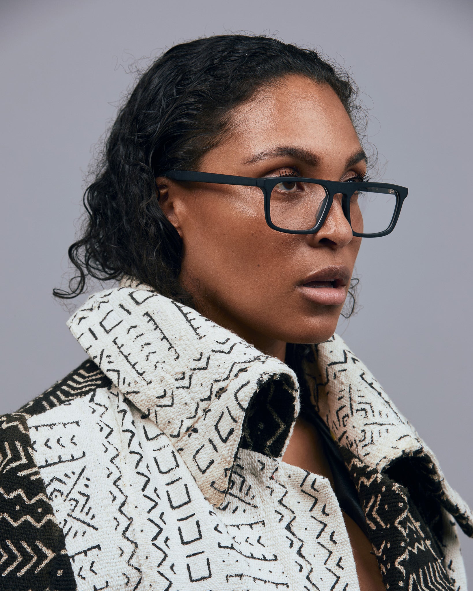 Gentleman Optical by Tribu Eyewear — matte black rectangular optical frame, female model on a grey background. 